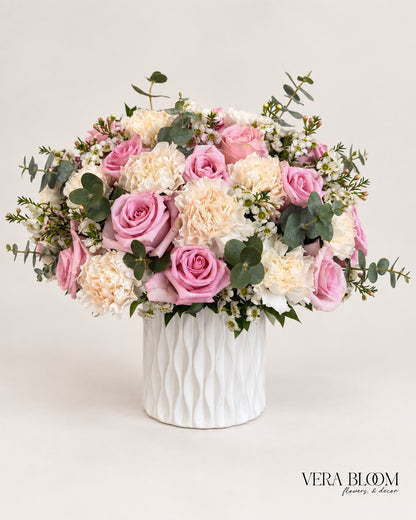 Pink Whisper pink roses and ivory carnations with eucalyptus in a white ceramic vase by Vera Bloom